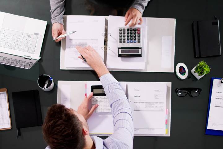 Consultor revisando checklist de conformidade trabalhista com gestor de RH em sala de reuniões corporativa, gráficos em tela, fotografia realista